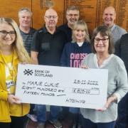 Charlotte Gilbert, from Marie Curie, receiving the cheque from Joyce Burns, Ian’s partner; watched by Eddie Hastie, Robin Haddow, Willie Muir, Paul Harley, Mike Hynd, Archie Muir and Anne Ewan. Picture by David Wardle.