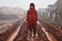 A child girl standing in the mud outside her shelter at Al-Ihsan refugee camp as Syrians enduring harsh winter at the camp in Idlib, Syria Agency/Getty Images