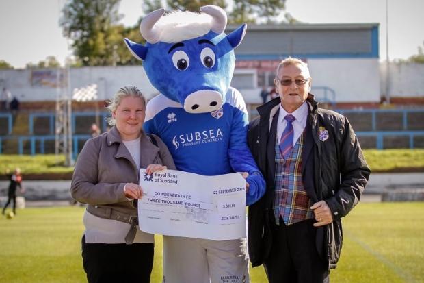 Zoe presents one of her cheques to Alex Anderson in 2018, with club mascot Bluebell the Coo.