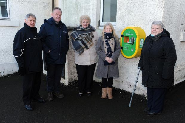 The new defibrillator on the wall at the end of Lumphinnans Primary School with Jim Martin, Alex Campbell, Elinor Martin, Head Teacher Ailsa Swankie and Amelia Howie