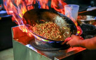 Chinese noodles and spices cooking in a wok. Credit: Canva
